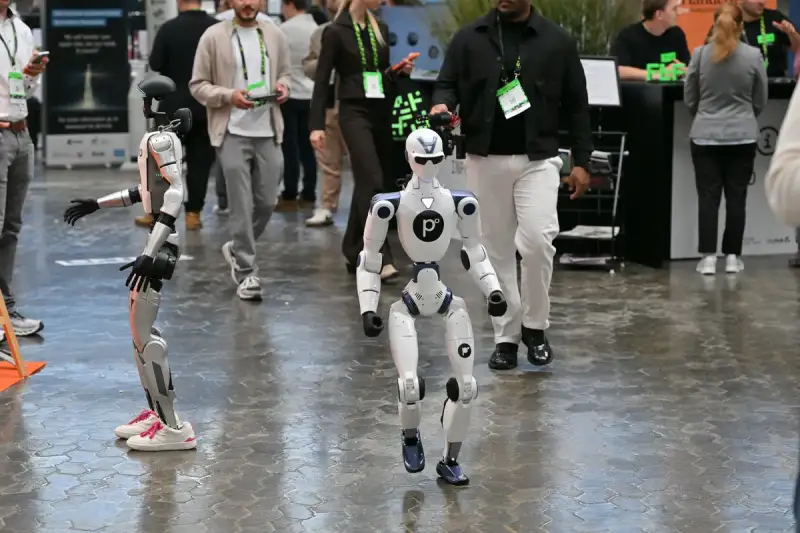 Unitree R1 en Unitree G1 · EVO lopen tussen de bezoekers door de hal van Future Tech Fest in Düsseldorf.