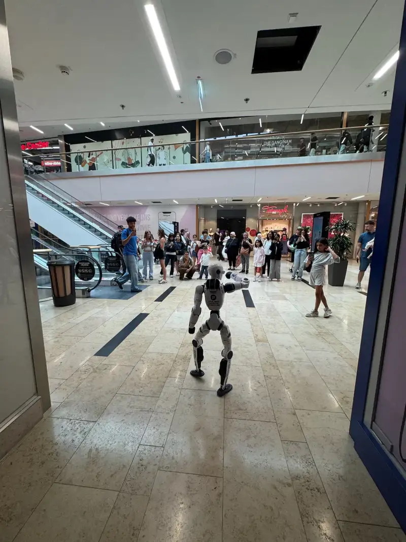 Publiek in een winkelcentrum filmt Unitree R1 tijdens een showslot.